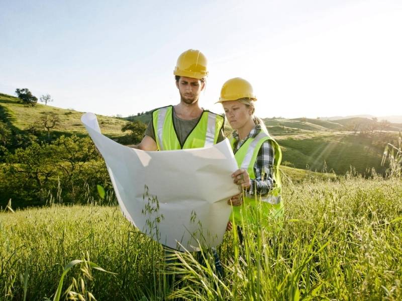 Survey professionals reviewing site plans in an open field during an ALTA survey planning and property evaluation process