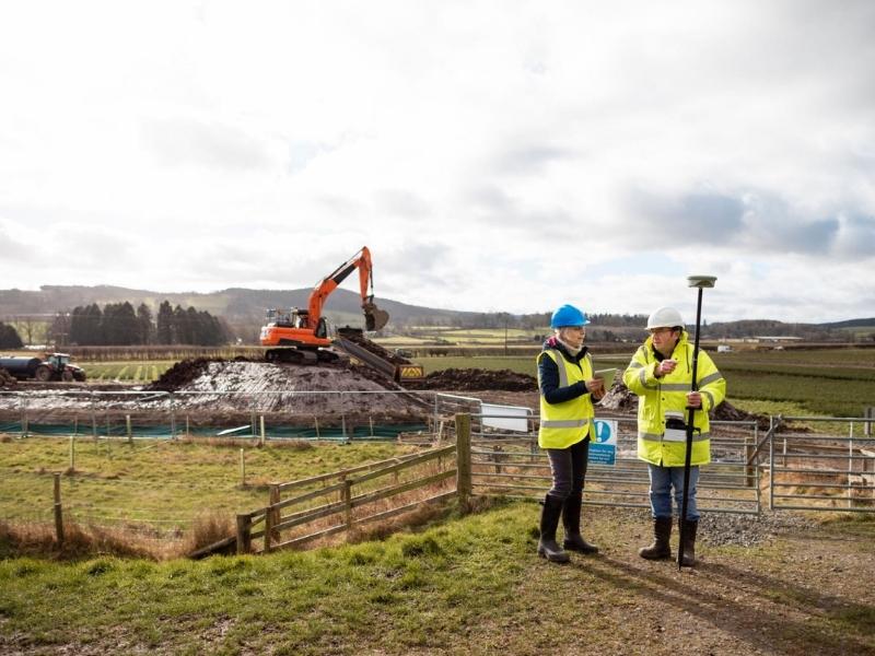 Licensed land surveyor team reviewing site measurements and survey data at an active construction and land development project