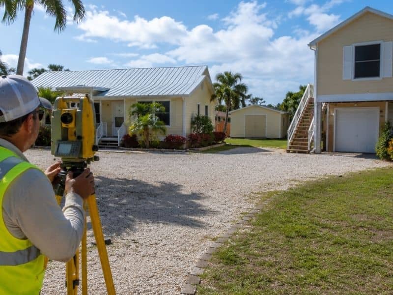 Surveyor documenting multiple buildings on a residential parcel for an elevation certificate in Fort Myers, Florida.